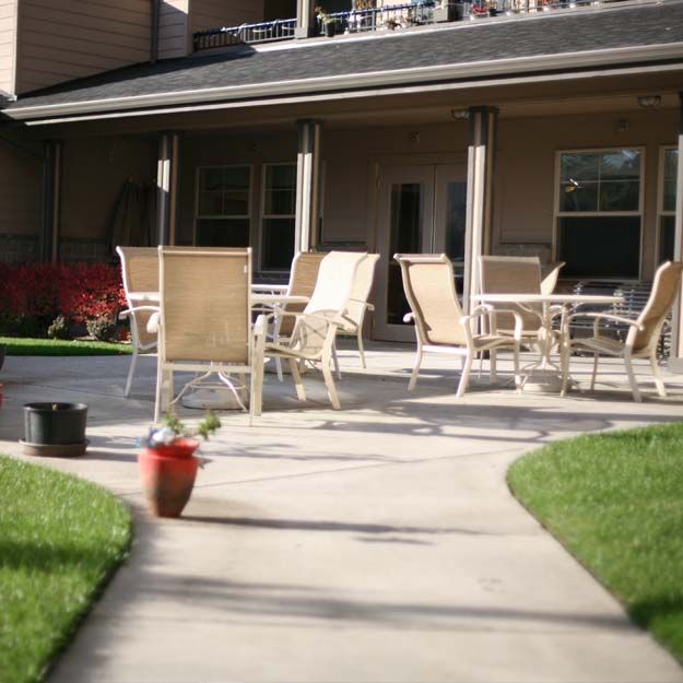 A patio with outdoor seating surrounded by a well-maintained lawn and potted plants.