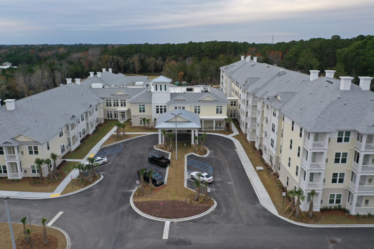 Aerial view of a large building complex with surrounding parking area and landscaping.