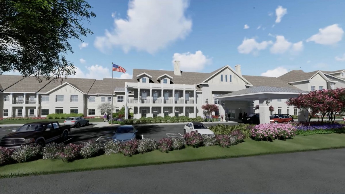 A large, elegant building with a garden and an American flag in front.