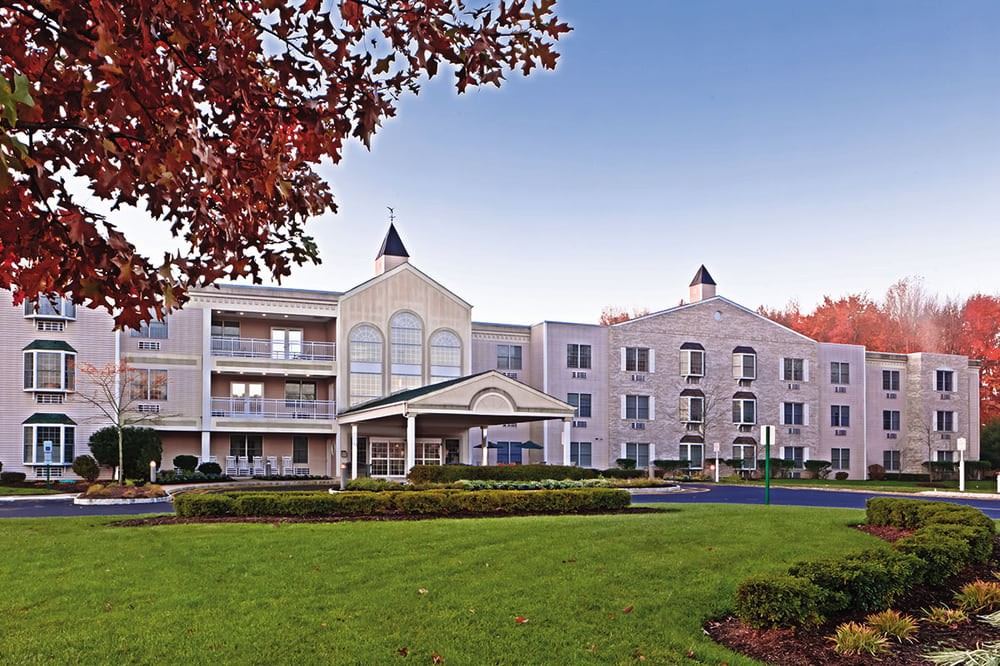 A hotel building with a well-maintained lawn, surrounded by autumn foliage.