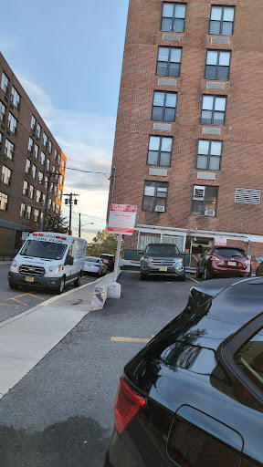 A view of a parking lot with various vehicles beside a brick building in an urban setting.