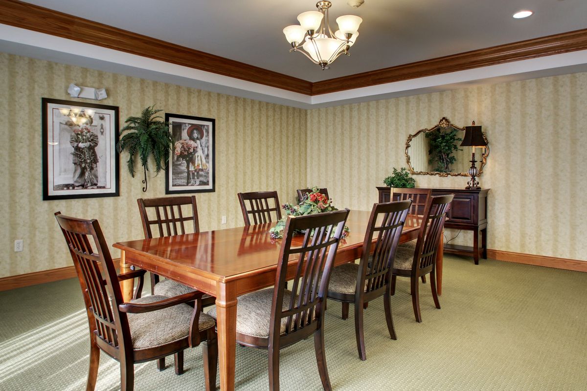 A well-decorated dining room with a wooden table and chairs, illuminated by a chandelier.