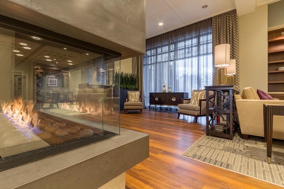 A luxurious and modern lounge area featuring a glass-enclosed fireplace and comfortable seating.