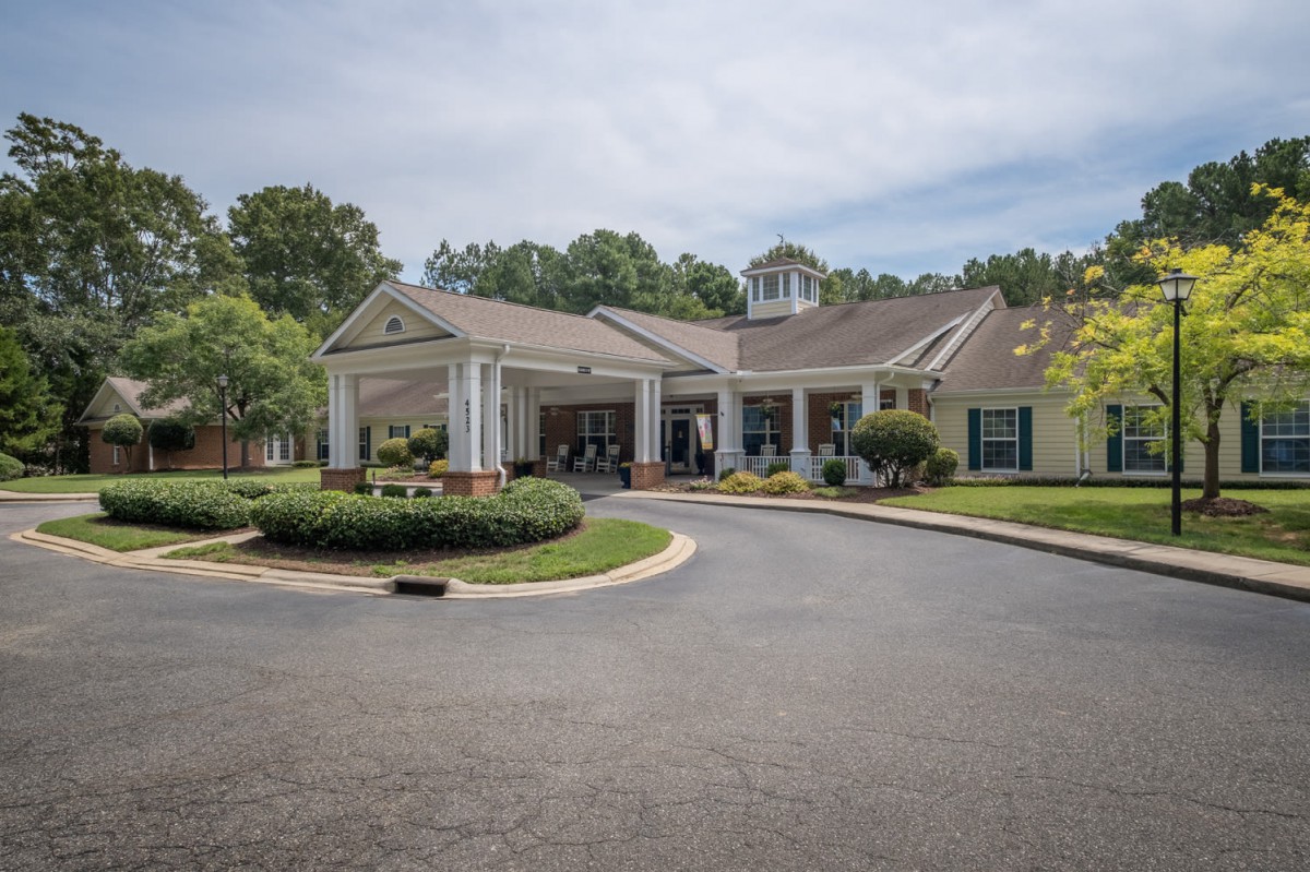 A residential building with a driveway and landscaped surroundings.