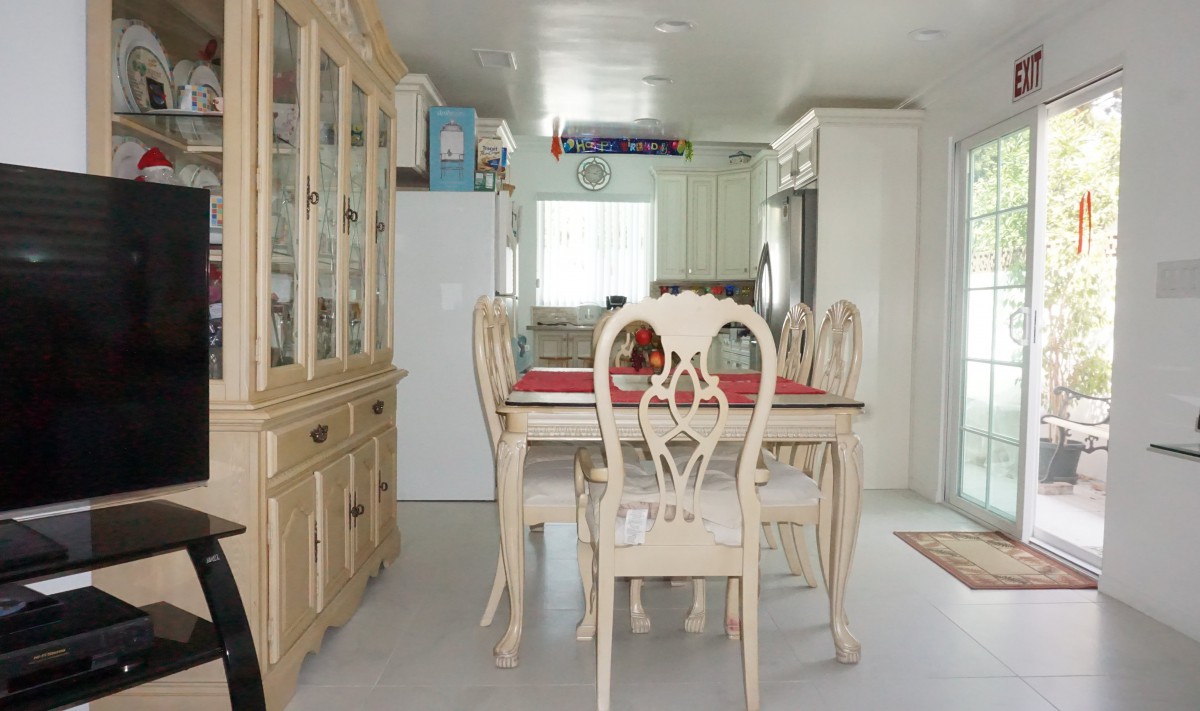 A bright dining area with elegant wooden furniture and a view into the kitchen.