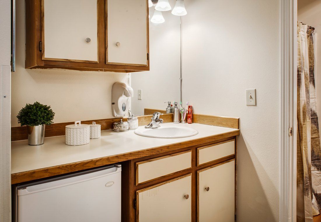 A cozy bathroom corner featuring a sink, mirror, and wooden cabinets.
