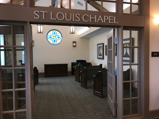 Interior view of St. Louis Chapel featuring wooden pews and a decorative window.