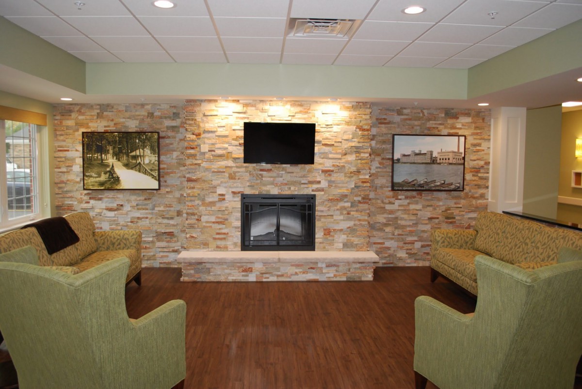 A cozy living room with a stone fireplace, television, and comfortable seating.