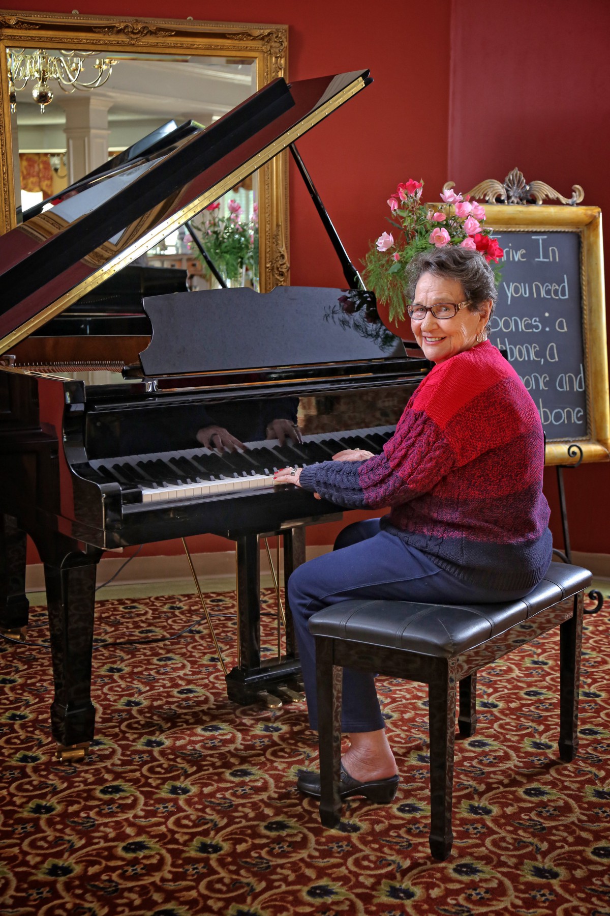 A person seated at a grand piano, ready to play indoors.