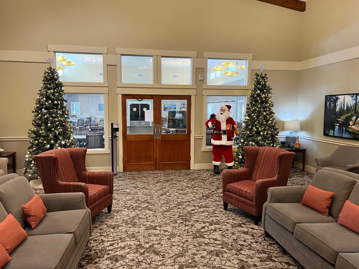 A festive lobby decorated with Christmas trees and a Santa Claus figure.