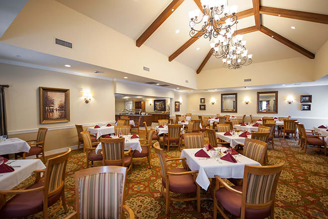 A well-appointed dining room with elegant chandeliers and neatly set tables.