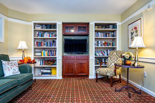 A cozy living room featuring bookshelves filled with books, a comfortable chair, and a television.
