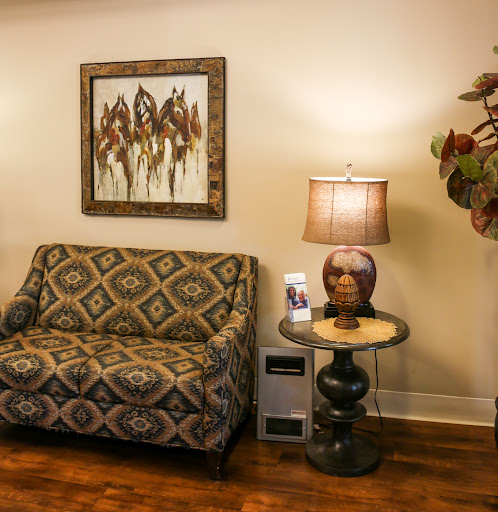 A cozy living room setup featuring a patterned sofa, a stylish lamp, and an abstract artwork on the wall.