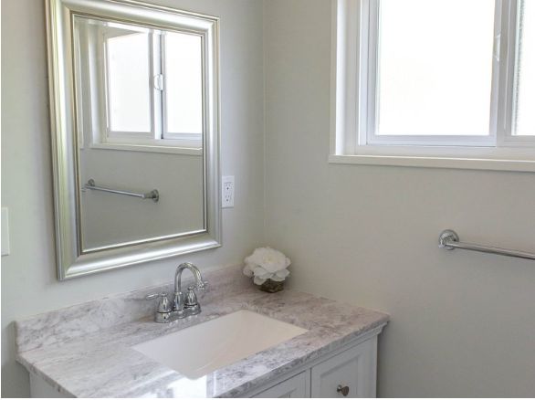 A minimalist bathroom with a marble countertop and a large mirror.