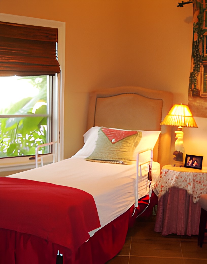 A cozy bedroom with a single bed, bedside table, and warm lighting.
