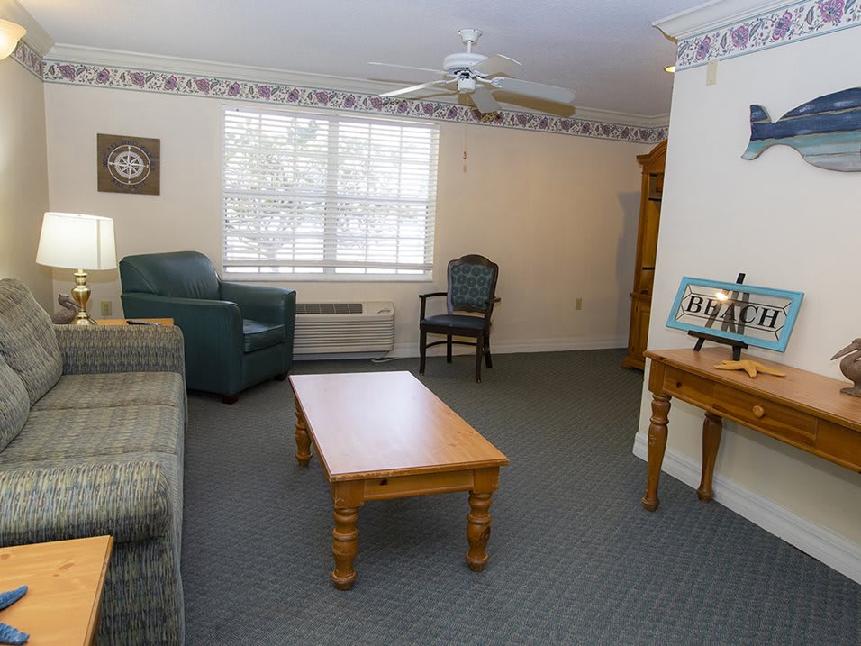 A simple living room featuring a sofa, armchair, and wooden coffee table with neutral decor.