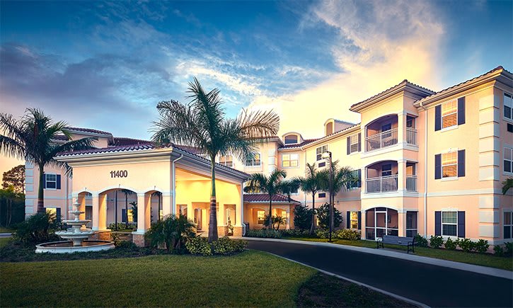 A luxurious residential building with palm trees at sunset.