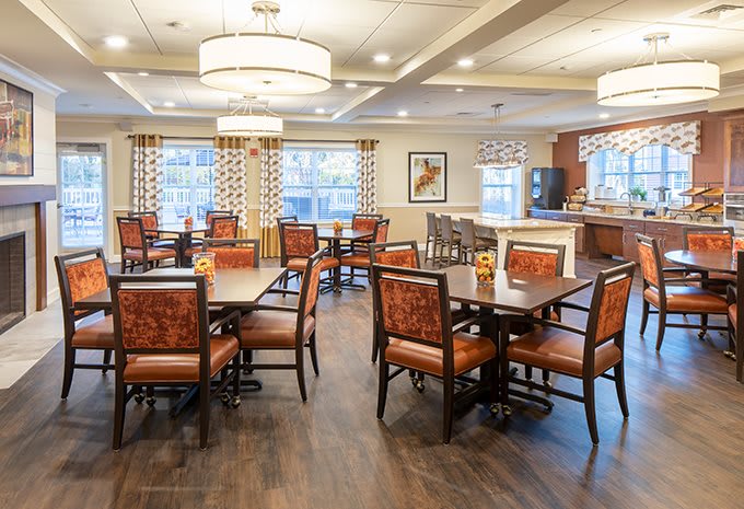 A spacious dining area with neatly arranged tables and chairs, warm lighting, and decorated walls.