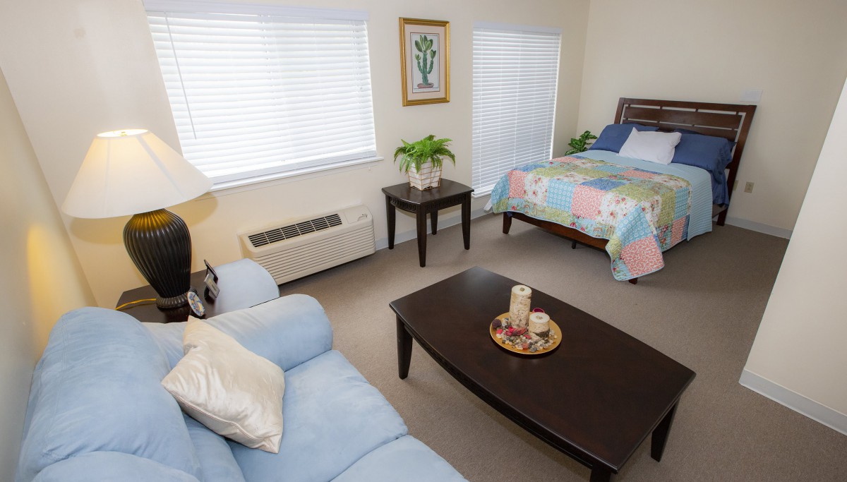 A cozy room featuring a bed, couch, and coffee table with decorative items.