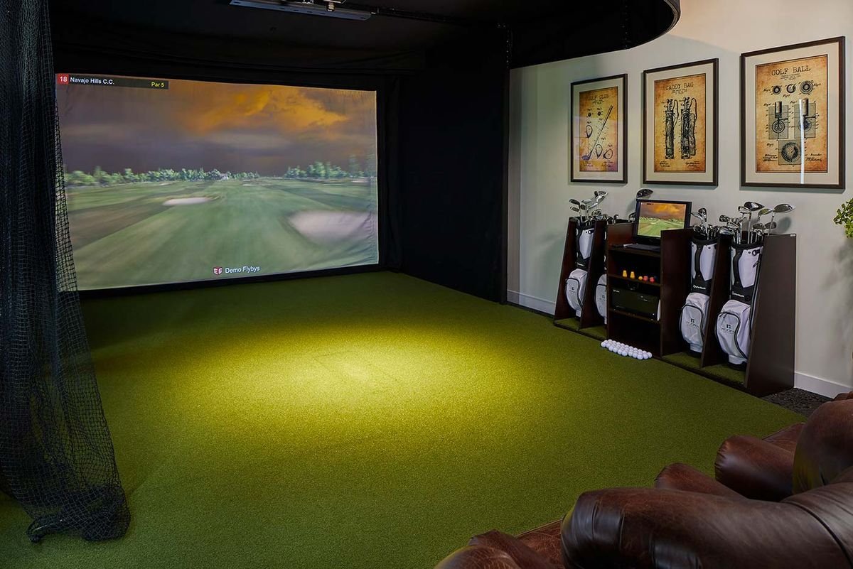 An indoor golf simulator setup with a projected virtual golf course.