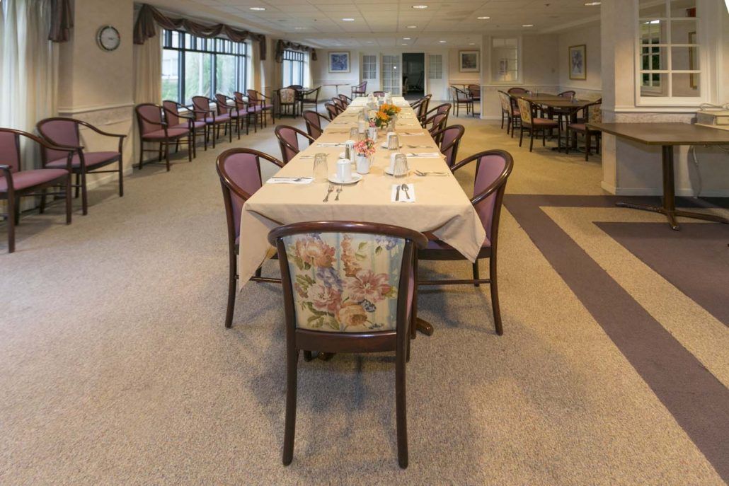An elegantly set dining room with a long table and upholstered chairs.