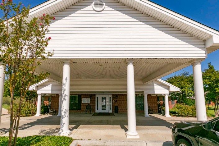 A building entrance with white columns and a gabled roof.