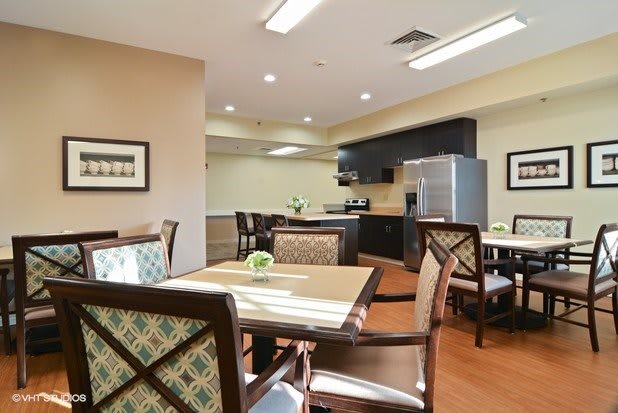 A modern dining area with a kitchen, featuring chairs and tables.