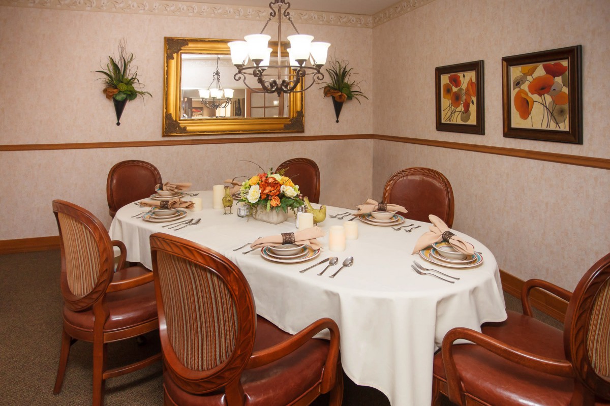 A cozy dining room with an elegantly set table and a chandelier overhead.