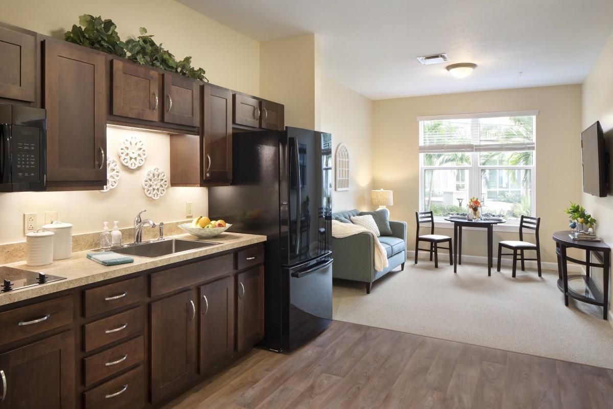A modern apartment with an open floor plan featuring a kitchen and living room area.
