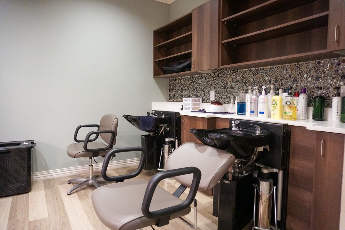 A modern salon interior featuring empty chairs and sinks, with hair products neatly displayed.
