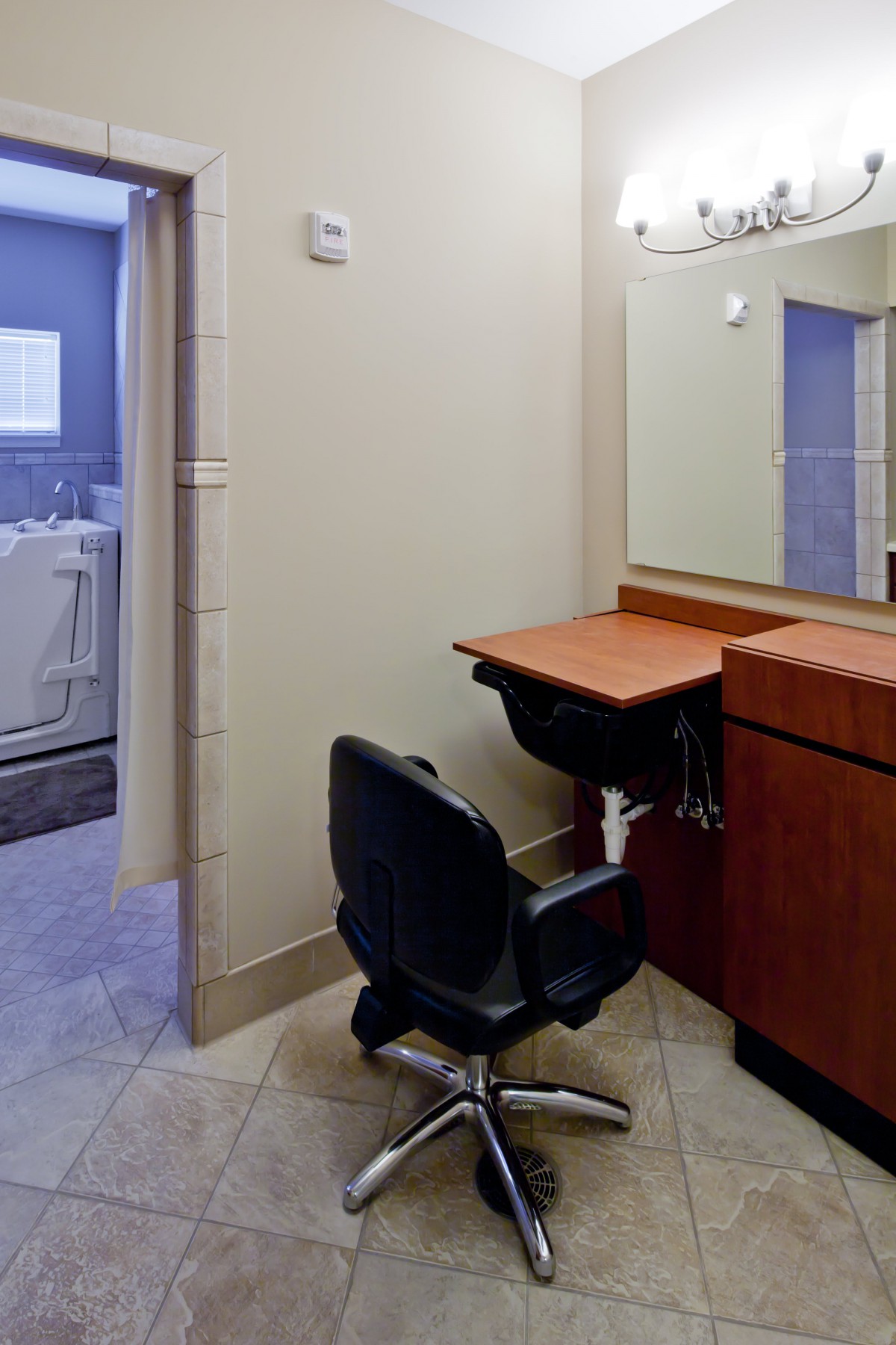 A view of a bathroom area with a vanity, chair, and mirror.