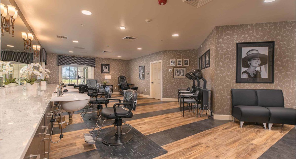 A modern hair salon interior featuring stylish chairs and mirrors on a wooden floor with sleek lighting.