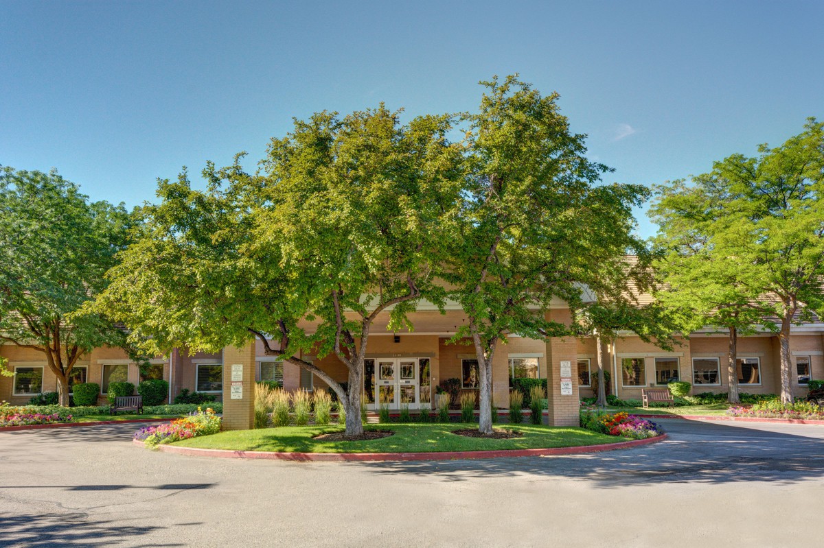 A welcoming building entrance surrounded by lush trees and landscaped greenery.