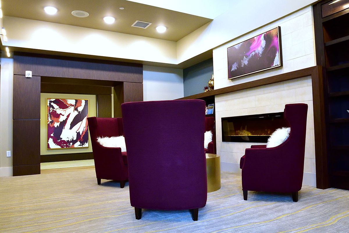 A modern seating area with purple chairs and a fireplace, decorated with contemporary artwork.