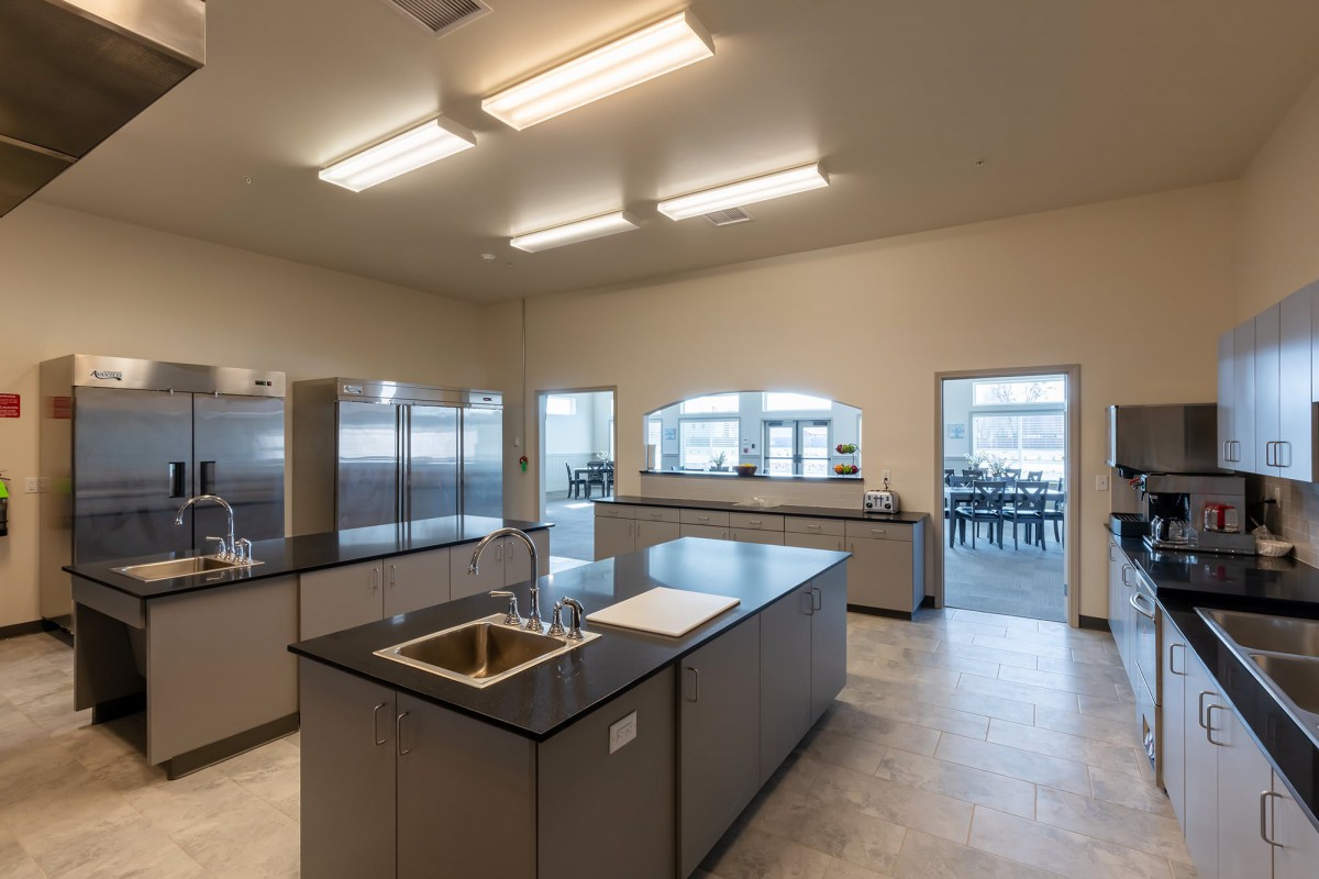 A modern kitchen featuring an island countertop and stainless steel appliances, illuminated by bright ceiling lights.