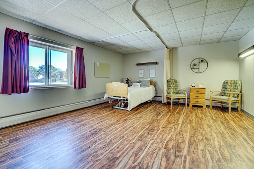 A well-lit hospital room designed for patient comfort, featuring a bed, chair, and storage.