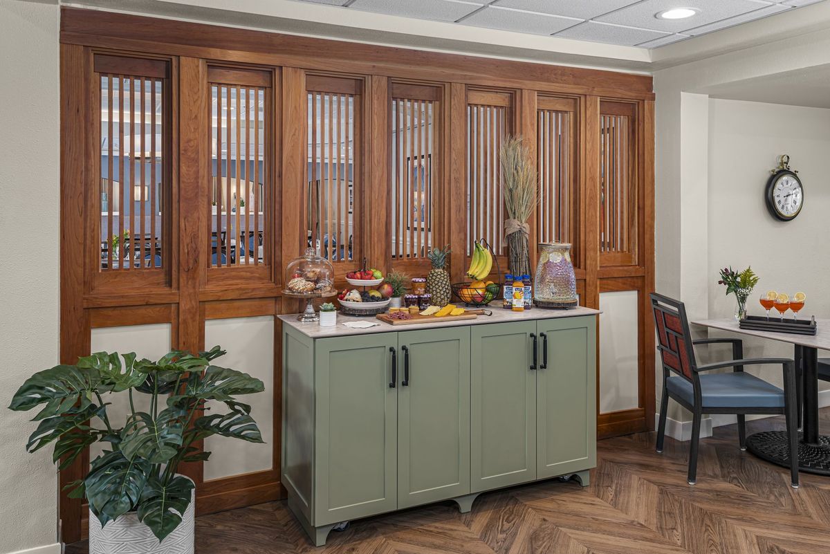 A stylish dining area with a green cabinet and decorative items, surrounded by wooden paneling.