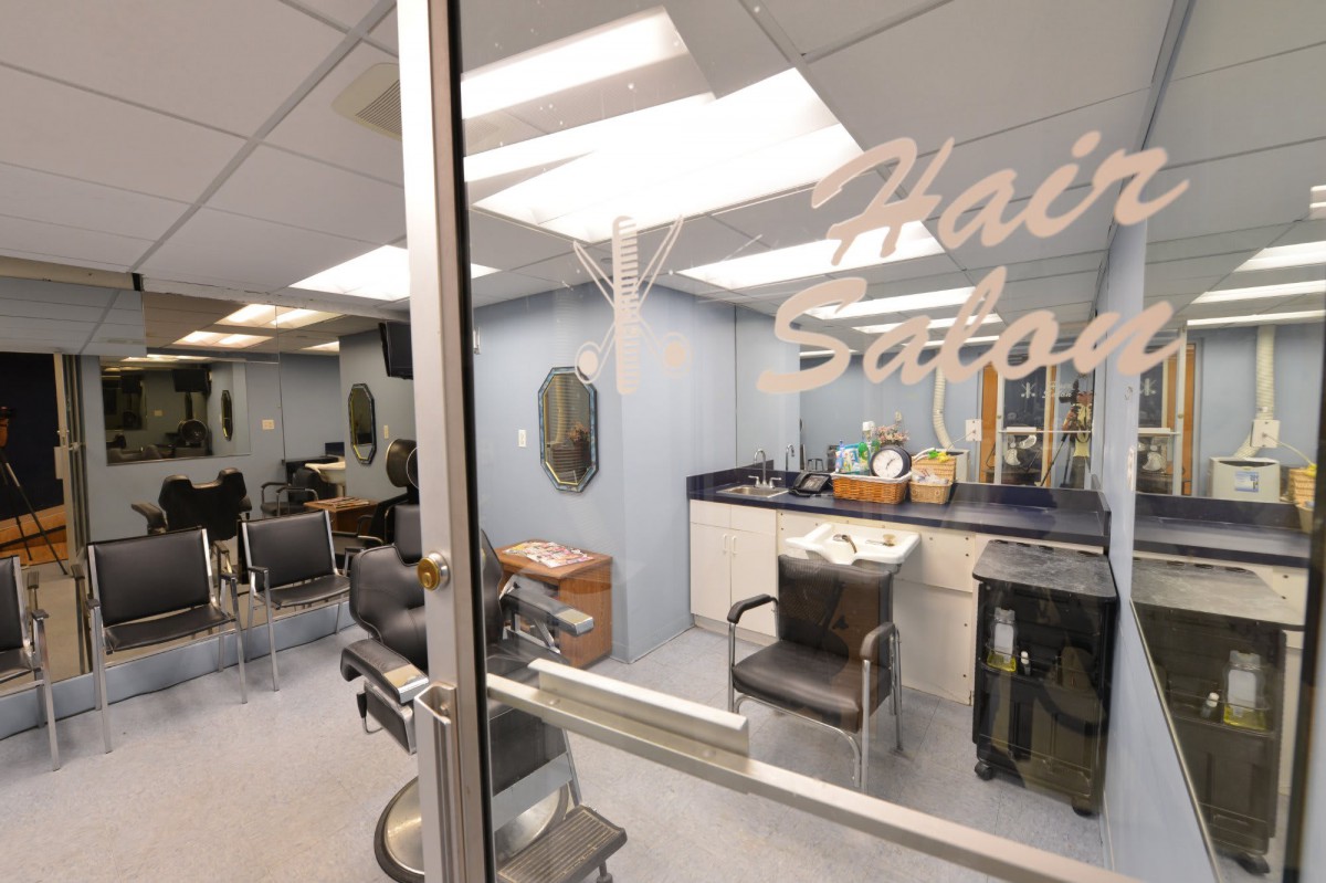 An interior view of a hair salon with chairs and styling stations visible through a glass door.