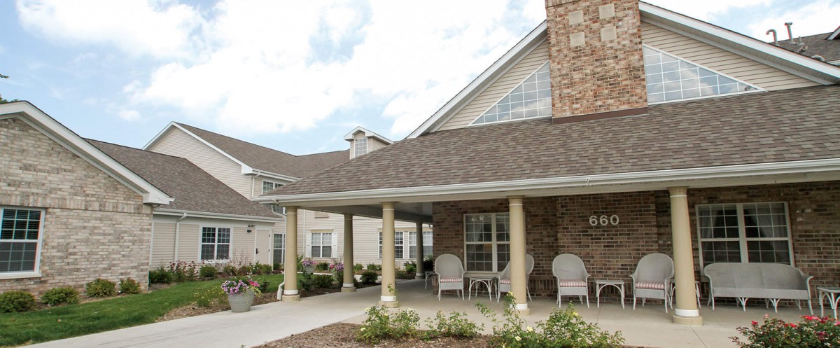 A residential building with a covered porch and a small garden in the front.