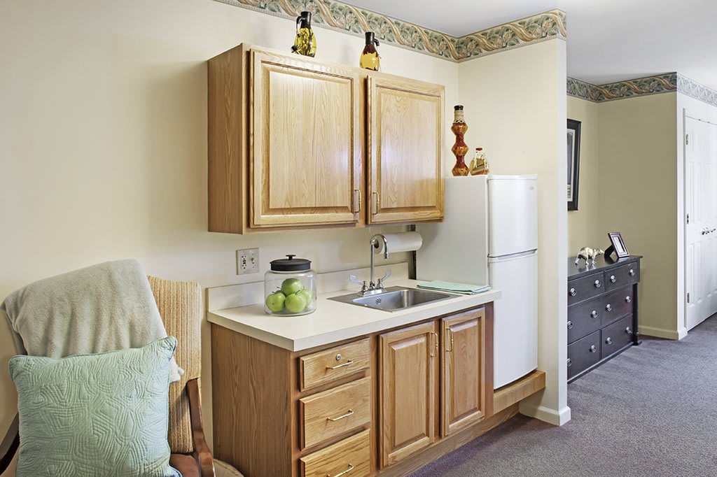 A small kitchen area featuring wooden cabinets, a white refrigerator, and a sink with countertop space.