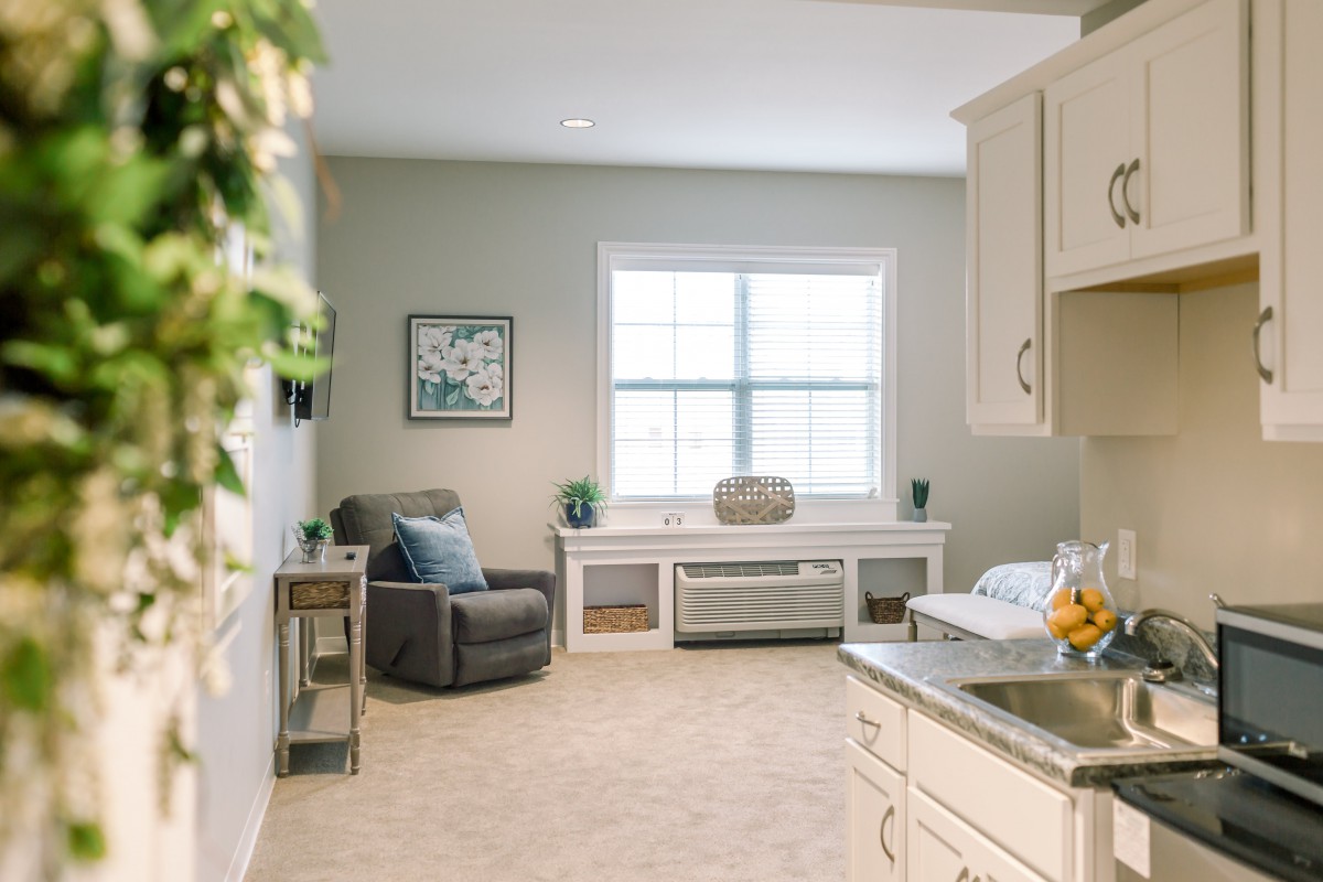 A cozy living room with a neutral color palette, featuring an armchair and large window.