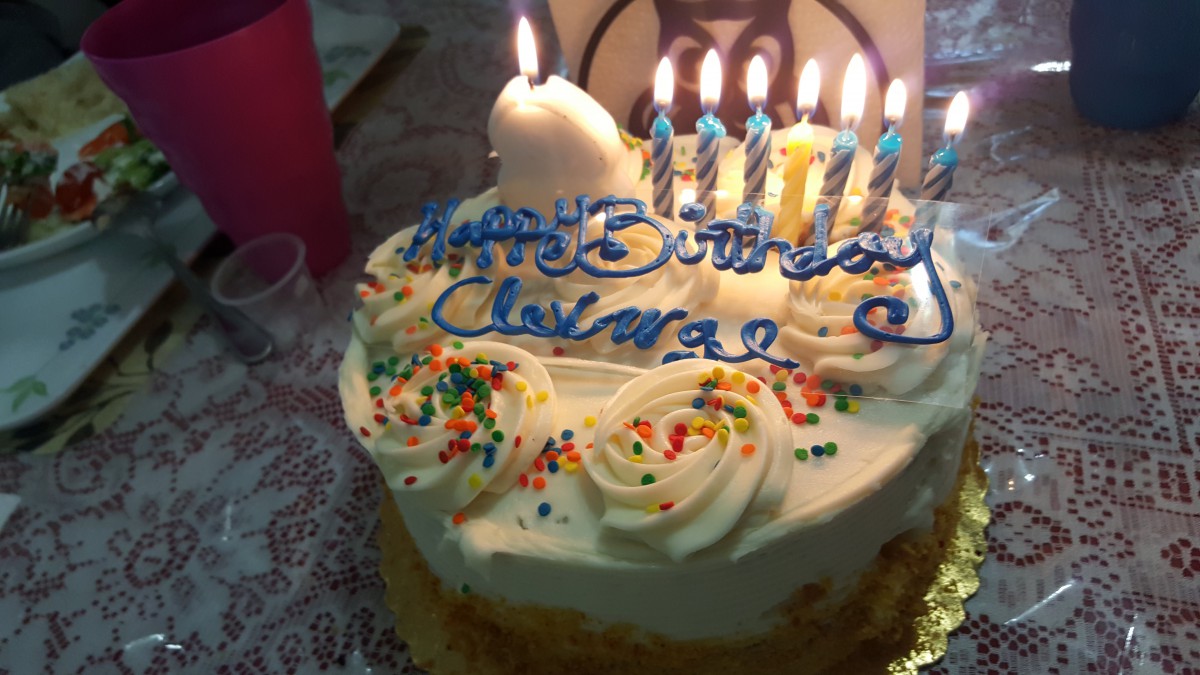 A decorated birthday cake with lit candles and colorful icing.