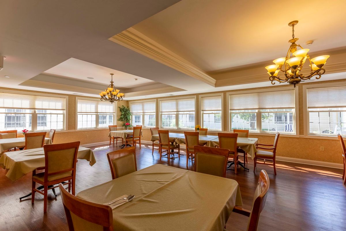 A well-lit restaurant dining room with neatly arranged tables and chairs next to large windows.