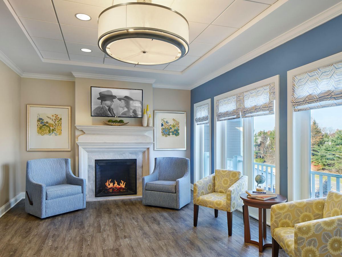 A cozy living room with modern decor, featuring a fireplace, comfortable armchairs, and large windows.