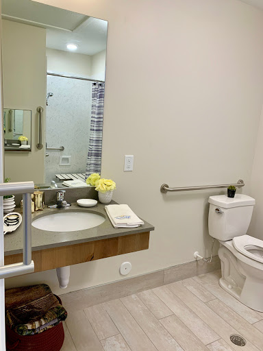 A modern bathroom featuring a sleek sink, a toilet, and accessibility features.