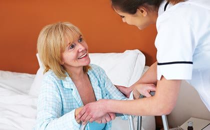 A nurse assisting and smiling at a patient in a healthcare setting.