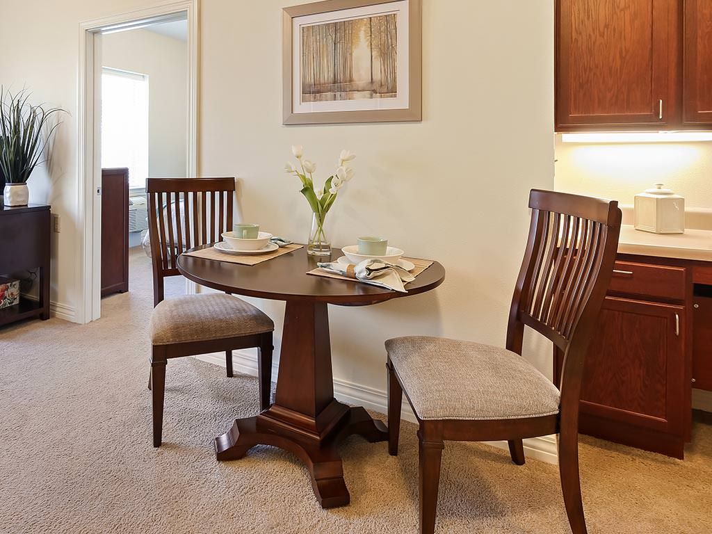 A cozy dining area with a round wooden table set for two.