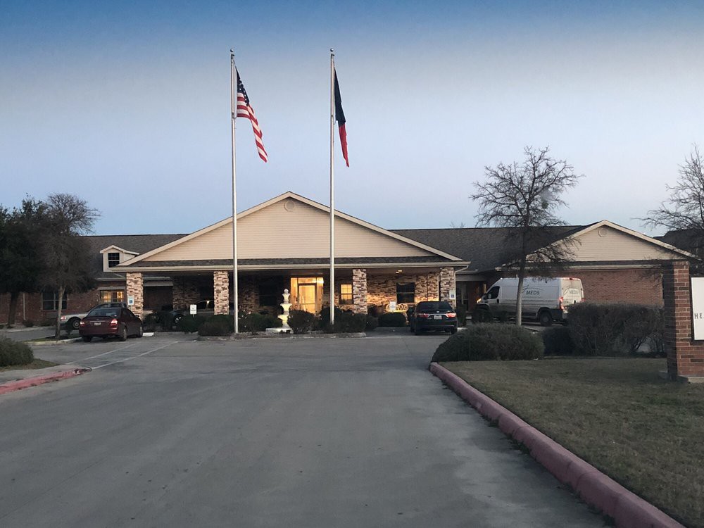 A building with flags in front and a parking lot at dusk.