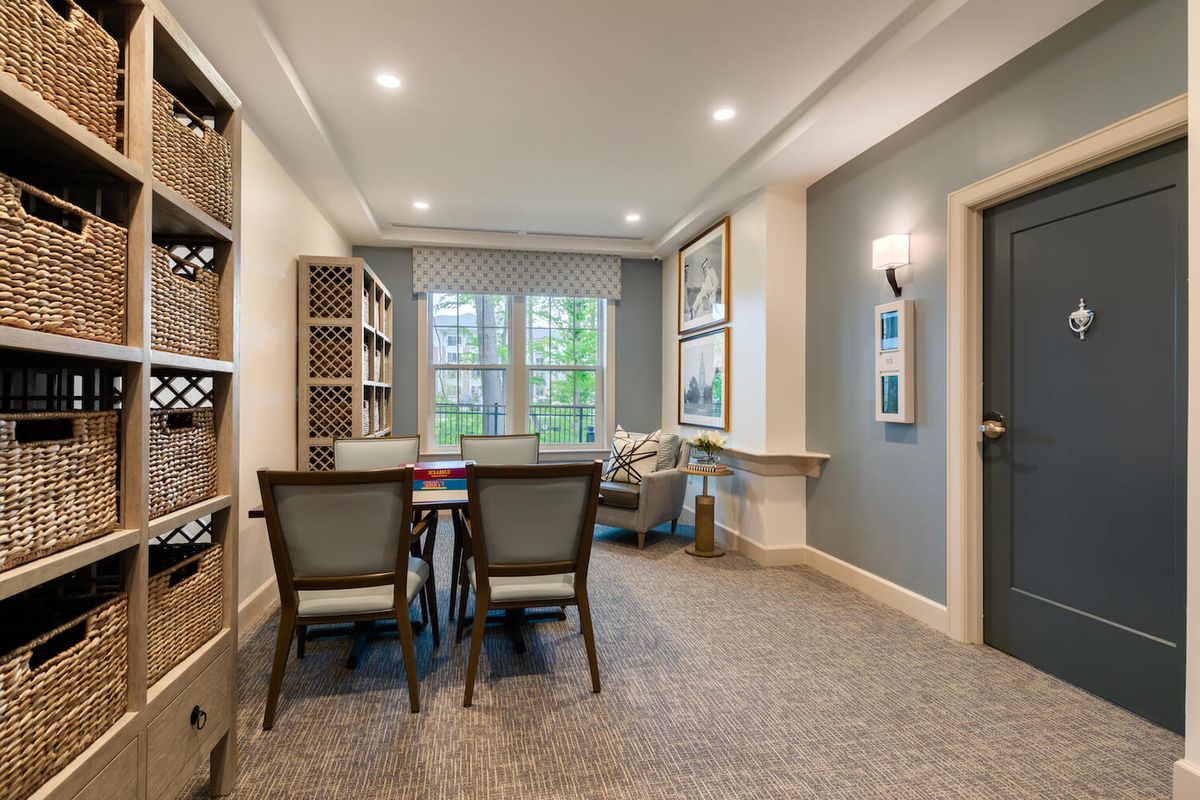 A cozy dining room with a table and chairs, surrounded by bookshelves and artwork.