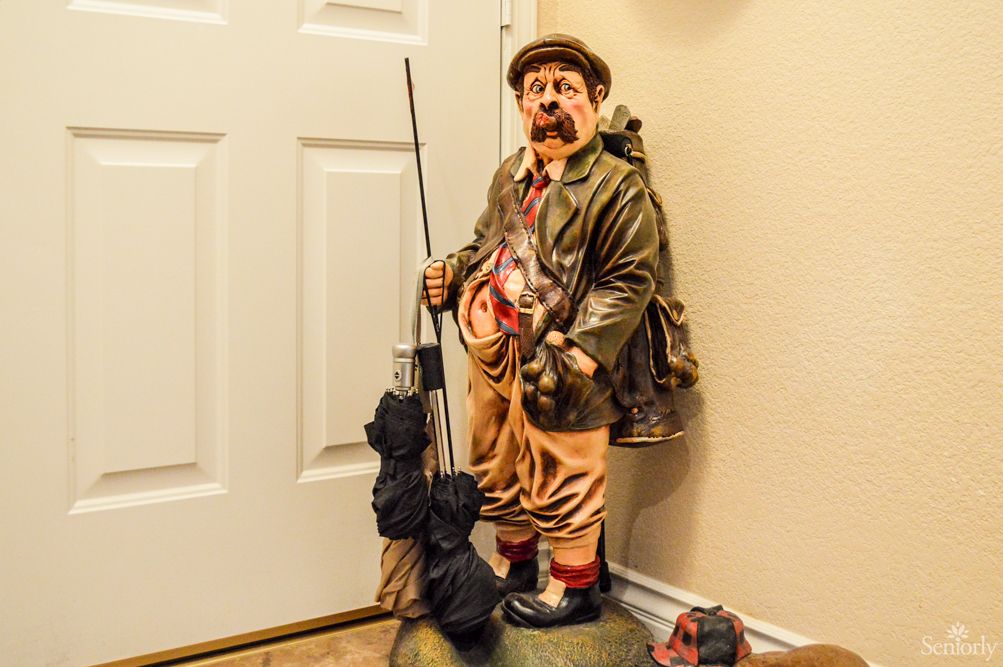 A whimsical statue of a fisherman with fishing gear displayed indoors.